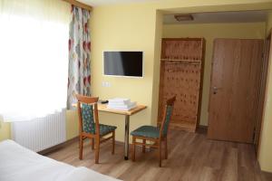 a hotel room with a table and chairs and a tv at Der Schildbacherhof in Hartberg