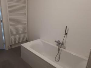 a white bathroom with a bathtub with a hose at Residentie Koen in Ostend +2 photos