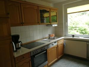 eine Küche mit Holzschränken und Spüle und einem Fenster in der Unterkunft FerienWohnung Gebhardt in Binz