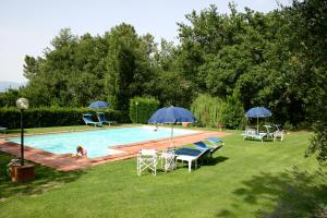 a pool with chairs and umbrellas in a yard at Le Giunchete in Cavriglia