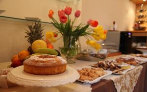 uma mesa com um bolo num prato e outros alimentos em Hotel Medici em Milazzo