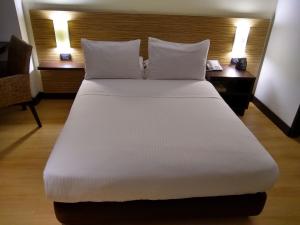 uma cama com lençóis brancos e almofadas num quarto em Scala 68 em Bogotá