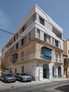 a building with two cars parked in front of it at Chapter 5 Hotel in Taʼ Xbiex