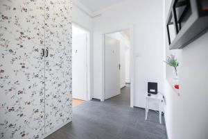 un pasillo con paredes blancas y papel pintado con motivos florales en Oberiter Apartments - in the heart of Zagreb en Zagreb