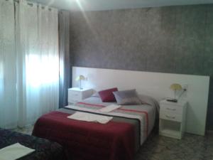 a hotel room with two beds and a window at Hostal Texas 2 in Fuentes de Ebro