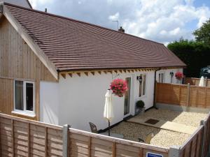 a white house with a wooden fence and an umbrella at New Inn Lane Holiday Cottages in Evesham