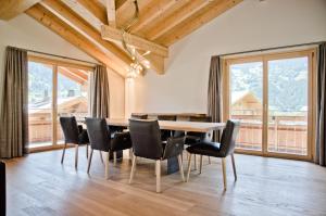 uma sala de jantar com mesa e cadeiras e janelas grandes em Chalet Rothenegg - GRIWA RENT AG em Grindelwald