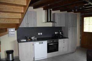 a kitchen with white cabinets and a white dishwasher at la forge d'andribet in Axiat