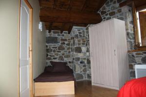 a bedroom with a stone wall with a bed and a cabinet at la forge d'andribet in Axiat