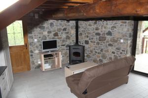 a living room with a couch and a stone wall at la forge d'andribet in Axiat
