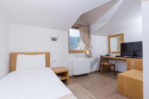 a bedroom with a bed and a desk with a television at Hotel Lirak in Tetovo