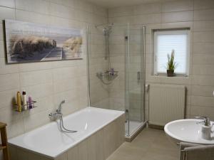 een badkamer met een bad, een douche en een wastafel bij Ferienwohnung Teltow 2 in Teltow