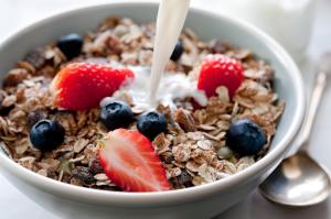 a bowl of granola with strawberries and blueberries and milk at Kinloch Hotel, Isle of Arran in Blackwaterfoot