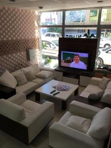 uma sala de estar com sofás brancos e uma televisão de ecrã plano em Asus Palmiye Otel em Adana