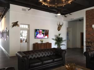 聖克勞德的住宿－亨特阿姆斯酒店，客厅配有真皮沙发和墙上的电视
