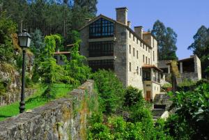 una casa vieja en una pared de piedra con una luz de la calle en Torre do Rio, en Caldas de Reis