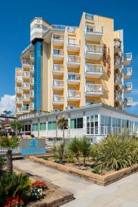 un gran edificio de apartamentos con plantas enfrente en Hotel Capri 3 Stelle SUPERIOR, en Lido di Jesolo