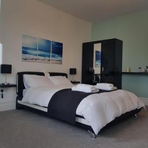 een slaapkamer met een groot bed met witte lakens bij Tippy's Guesthouse in Newquay