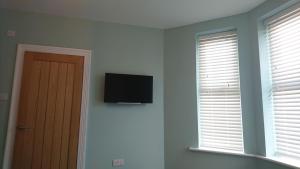 a room with a television on the wall and a door at Tippys Guesthouse in Newquay