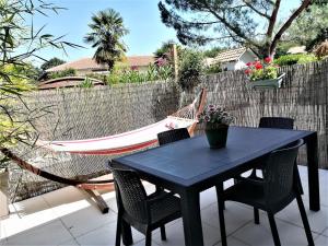 une table et des chaises noires ainsi qu'un hamac sur la terrasse. dans l'établissement Lac et Nature, à Sanguinet