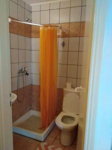 uma casa de banho com um WC e uma cortina de chuveiro laranja em The Village em Igoumenitsa