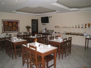a dining room with tables and chairs and a television at Hotel Colonial in Pôrto Real