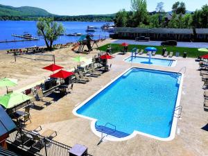 a pool with chairs and umbrellas next to a lake at Scotty's Lakeside Resort in Lake George