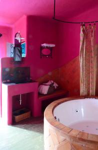 baño de color rosa caliente con bañera y TV en Hotel Alma de Romero en Carranza