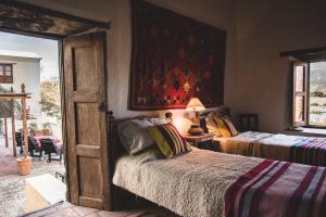 a bedroom with two beds and a painting on the wall at Casa del Tejedor in Cachí