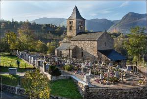 uma velha igreja com uma torre e um cemitério em la forge d'andribet em Axiat