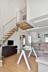 a living room with a glass table and a staircase at Apartamentos Centro Cordoba in Córdoba