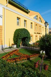 a yellow building with an arch and flowers at Arkadia Hotel in Saint Petersburg