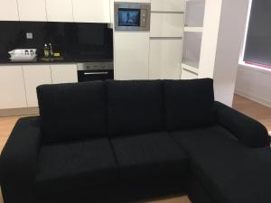 a black couch in a living room with a kitchen at Invicta House Maia in Maia