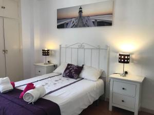 um quarto com uma cama branca, 2 mesas de cabeceira e 2 candeeiros. em Mare Nostrum Beach Vistas al Mar Terraza Fibra Optica, , Aparcamiento em Málaga
