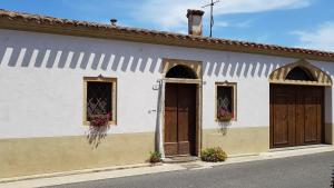 - un bâtiment blanc avec deux portes et deux fenêtres dans l'établissement L'AGRUMETO SEGRETO, à Riola Sardo