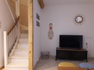a living room with a tv and a staircase at La Coulée Douce - Chez Antoine in Castelnaudary
