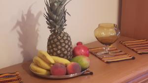 un bol de fruits sur une table avec un ananas et un verre dans l'établissement motylek, à Łódź