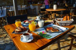 a wooden table with breakfast foods and drinks on it at Marzi Boutique Hotel in Nerátza