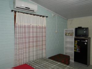 a room with a bed and a tv and a refrigerator at Recanto do Sol Pousada in Capão da Canoa