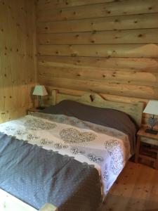 a bed in a room with a wooden wall at Le Syote in Xonrupt-Longemer