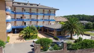 a hotel with a blue building and palm trees at Hotel Montemar in Noja