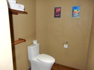 a bathroom with a toilet with two pictures on the wall at Casa Arcoiris Zihuatanejo B&B in Zihuatanejo