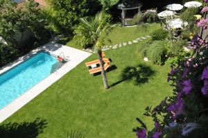 einen Pool in einem Garten mit einer Palme und einer Bank in der Unterkunft Hotel Verena in Lana
