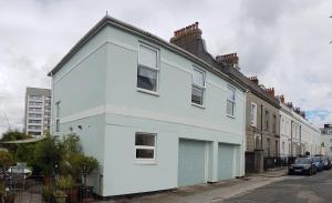 a white house with a garage on a street at The Coach House in Plymouth