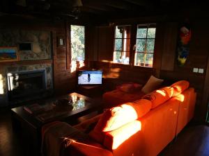 ein Wohnzimmer mit einem orangenen Sofa und einem TV in der Unterkunft El Rincon de tus Sueños in El Espinar