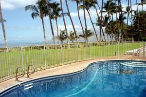 a swimming pool with palm trees and the ocean at Hale Kai O'Kihei 219 in Kihei
