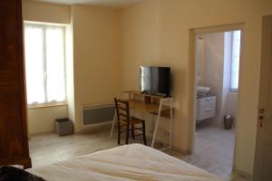 a bedroom with a desk with a television and a table with chairs at Les Chambres d'Eugénie in Poyanne