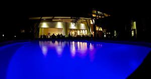 Ecolux Boutique Hotel في كوماتيبورت: حمام سباحة أزرق في الليل مع مبنى في الخلفية