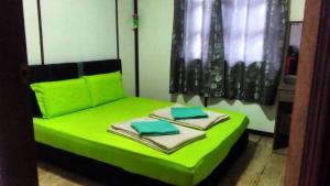 Una cama verde con toallas encima. en Dongorit Cabin House 1 en Kundasang