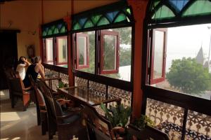 um grupo de pessoas sentadas em uma mesa olhando para fora das janelas em Sahi River View Guest house em Varanasi